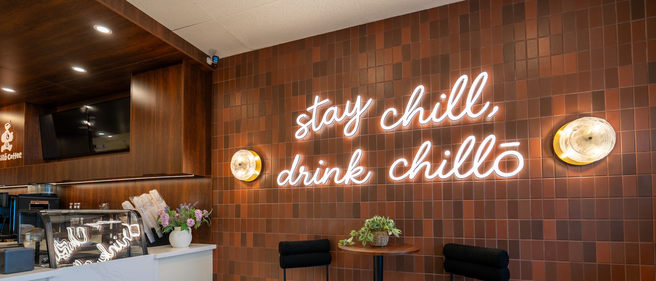 The 'stay chill, drink chillō' neon sign on the terracotta tiled wall at Chillō café